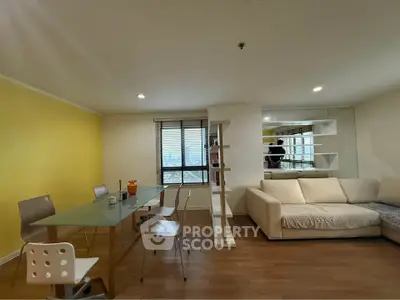 Modern living room with yellow accent wall and glass dining table