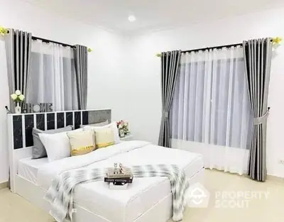 Elegant bedroom with modern decor and large windows, featuring stylish curtains and cozy bedding.