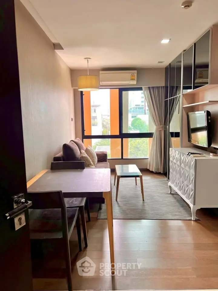 Modern living room with stylish decor and large windows offering city views.