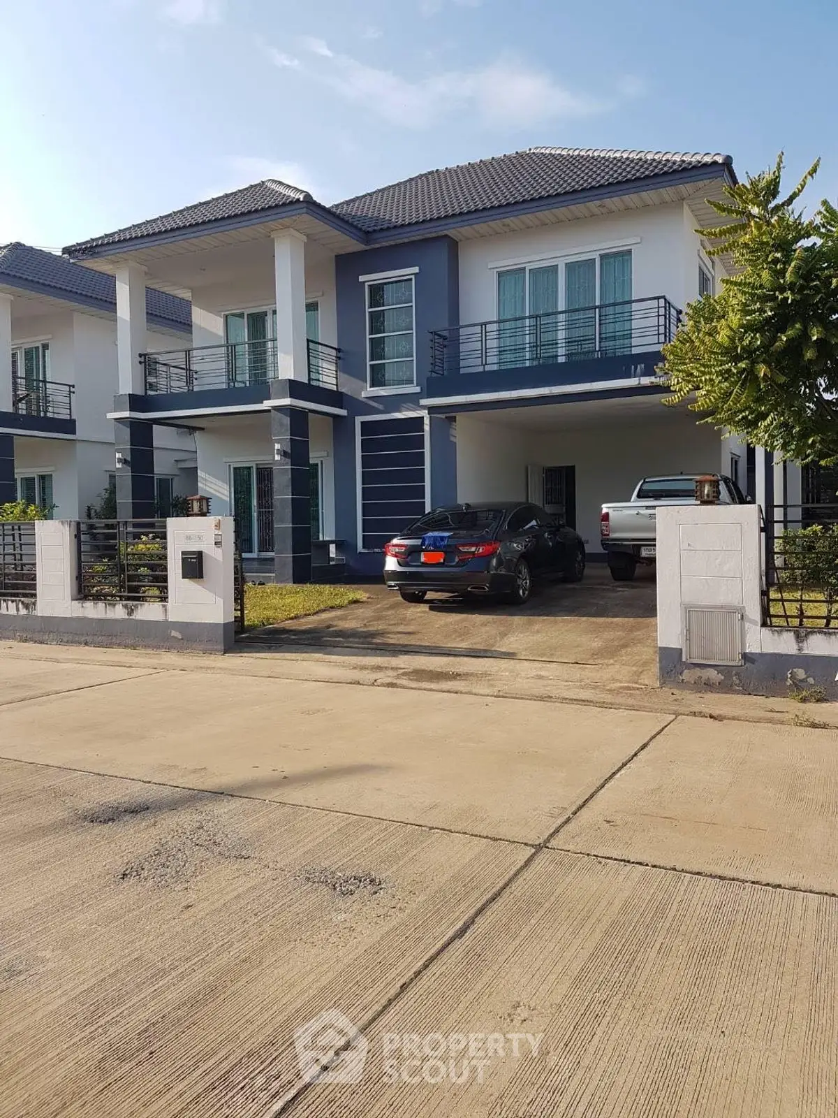 Modern two-story house with driveway and parked cars in a suburban neighborhood.