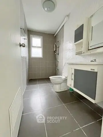 Modern bathroom with sleek fixtures and neutral tiles, featuring a spacious shower area.