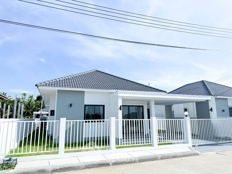 Modern single-story house with sleek design and fenced yard in sunny neighborhood.