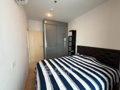 Modern bedroom with striped bedding and sleek wardrobe in a cozy apartment.