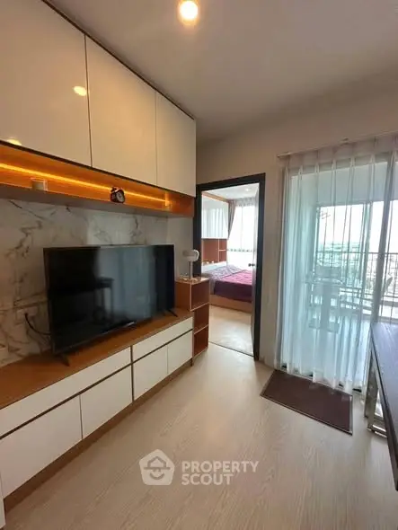 Modern living room with TV, stylish cabinetry, and balcony view in a contemporary apartment.