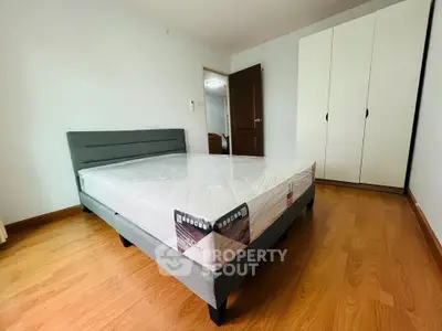 Spacious bedroom with wooden flooring and modern furniture, featuring a large bed and sleek wardrobe.