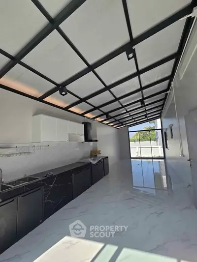 Sleek modern kitchen with marble flooring and black cabinetry, featuring a spacious open layout and ample natural light.