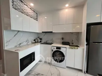 Modern kitchen with sleek white cabinets, marble backsplash, and integrated appliances.