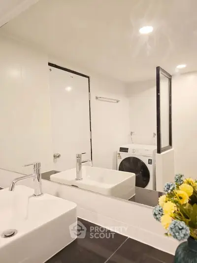 Modern bathroom with dual sinks and washing machine, featuring sleek design and bright lighting.