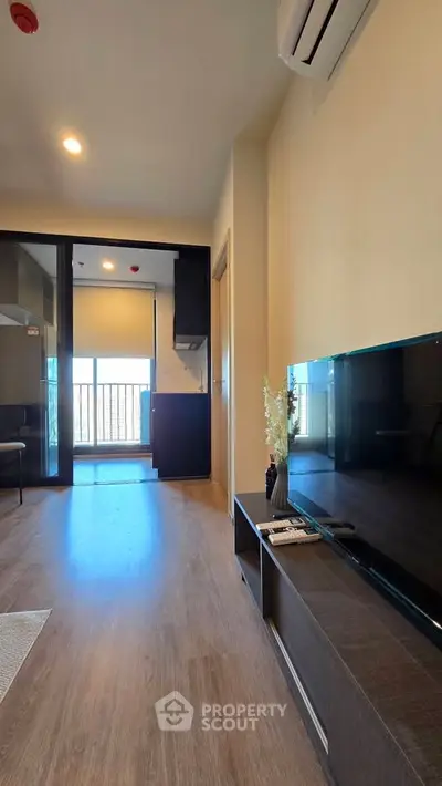 Modern living room with sleek TV unit and balcony view in stylish apartment.