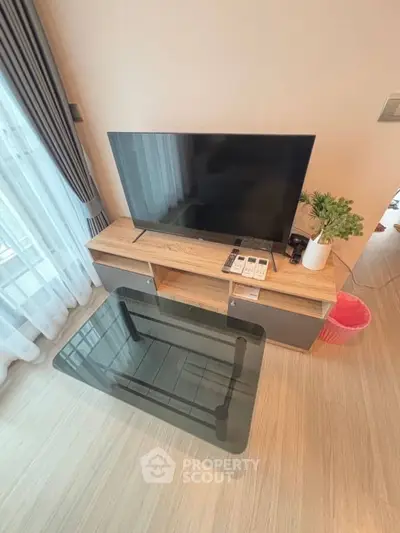 Modern living room with sleek TV stand and glass coffee table, perfect for stylish urban living.