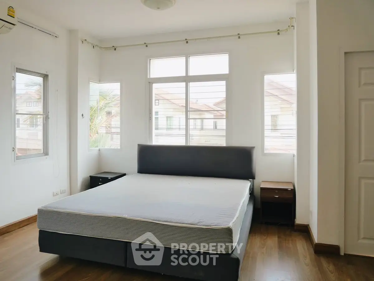 Spacious bedroom with large windows and modern bed frame, perfect for natural light lovers.