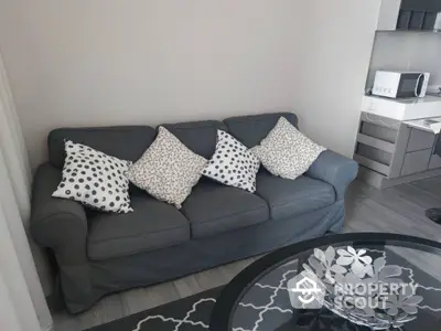 Chic modern living space with a stylish grey sofa adorned with patterned cushions, sleek furnishings, and a decorative centerpiece on the coffee table.