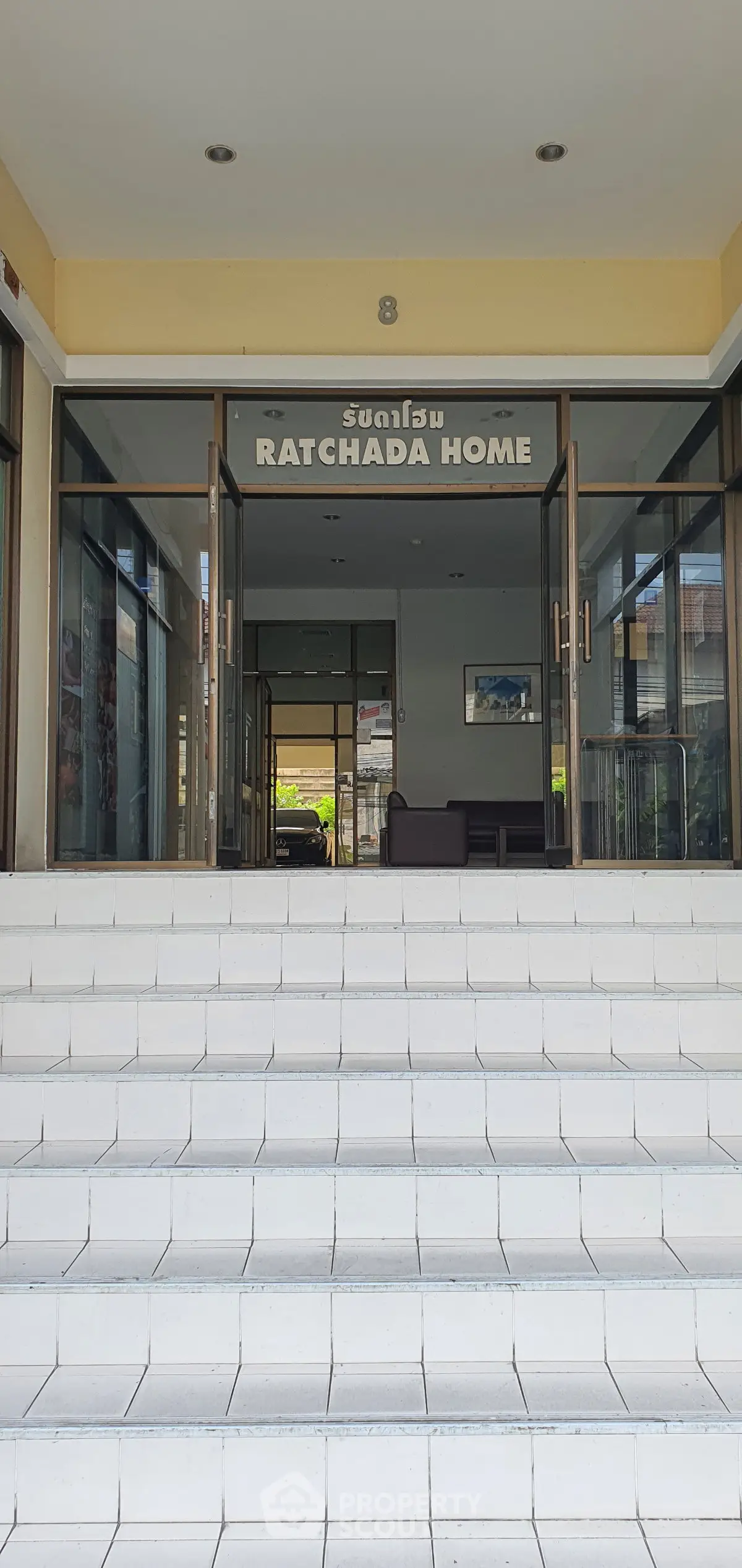 Inviting entrance of Ratchada Home with welcoming steps and glass doors.