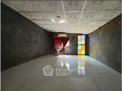 Spacious room with decorative ceiling tiles and colorful window accents