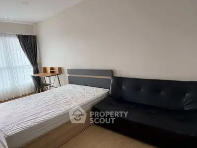 Modern bedroom with bed, black sofa, and study desk near window with curtains.