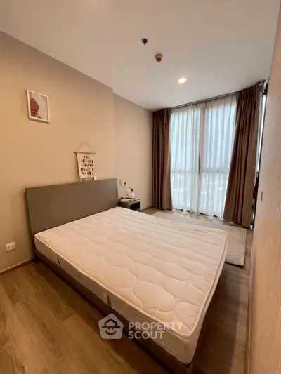 Spacious bedroom with large window and modern decor in a stylish apartment.