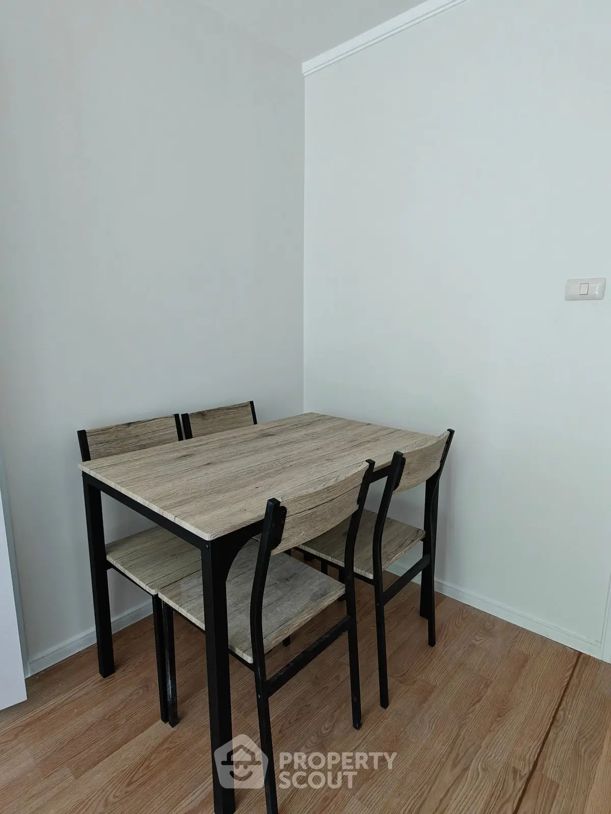 Modern dining area with minimalist wooden table and chairs on sleek wooden flooring.