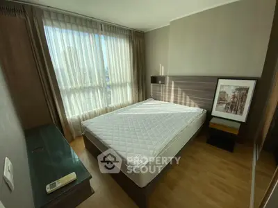 Cozy bedroom with large window and modern decor in a bright apartment.