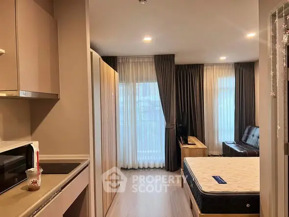 Modern studio apartment with open layout, featuring a cozy living area and kitchenette.
