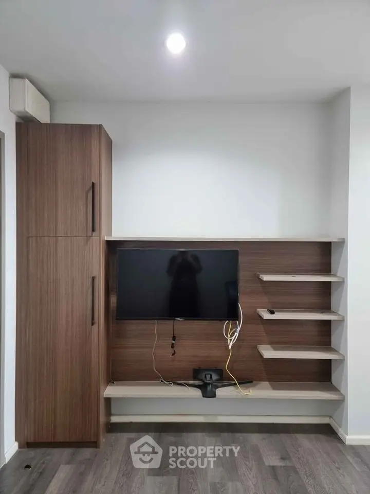 Modern living room with sleek wooden TV unit and shelves, perfect for stylish urban living.