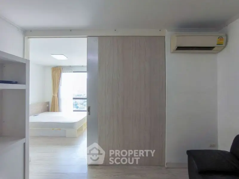 Modern apartment interior with sliding door and air conditioning, featuring a bright bedroom view.