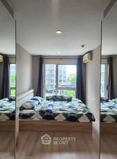 Modern bedroom with large windows and mirrored closet doors in urban apartment