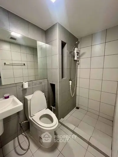 Modern bathroom with sleek tiles and walk-in shower in contemporary apartment.