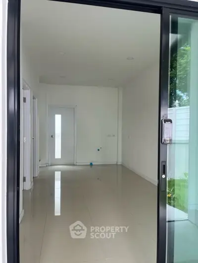 Spacious empty room with sliding glass door and glossy tile flooring