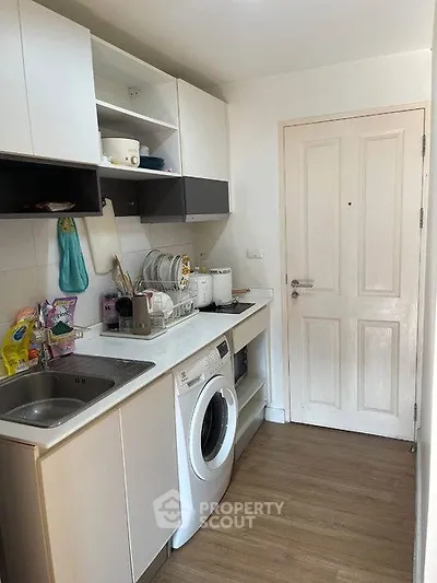 Compact kitchen with modern appliances and washing machine in cozy apartment