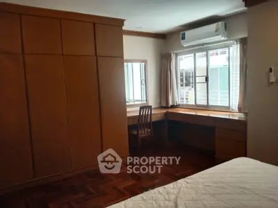 Spacious bedroom with wooden furniture and large window for natural light