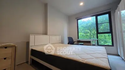 Spacious bedroom with large window and garden view, featuring modern furniture and natural light.