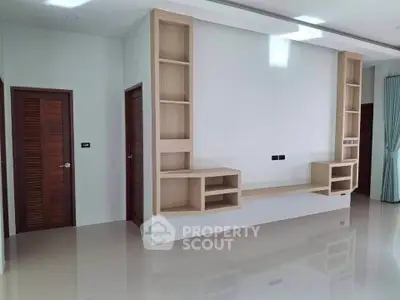 Modern minimalist living room with built-in wooden shelves and glossy floor finish.