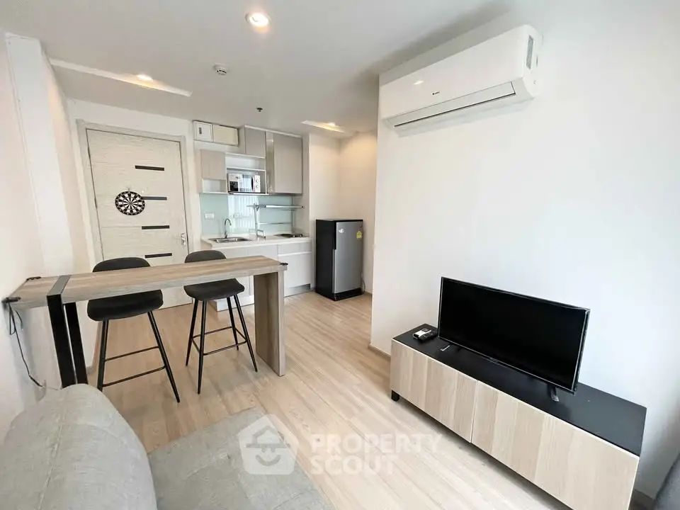 Modern living room with open kitchen, featuring sleek furniture and minimalist design.