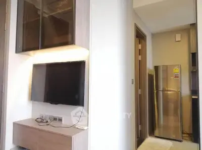 Modern apartment interior with wall-mounted TV and sleek kitchen area