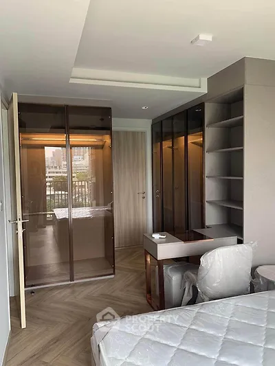 Modern bedroom with glass wardrobe and city view, featuring sleek design and natural light.