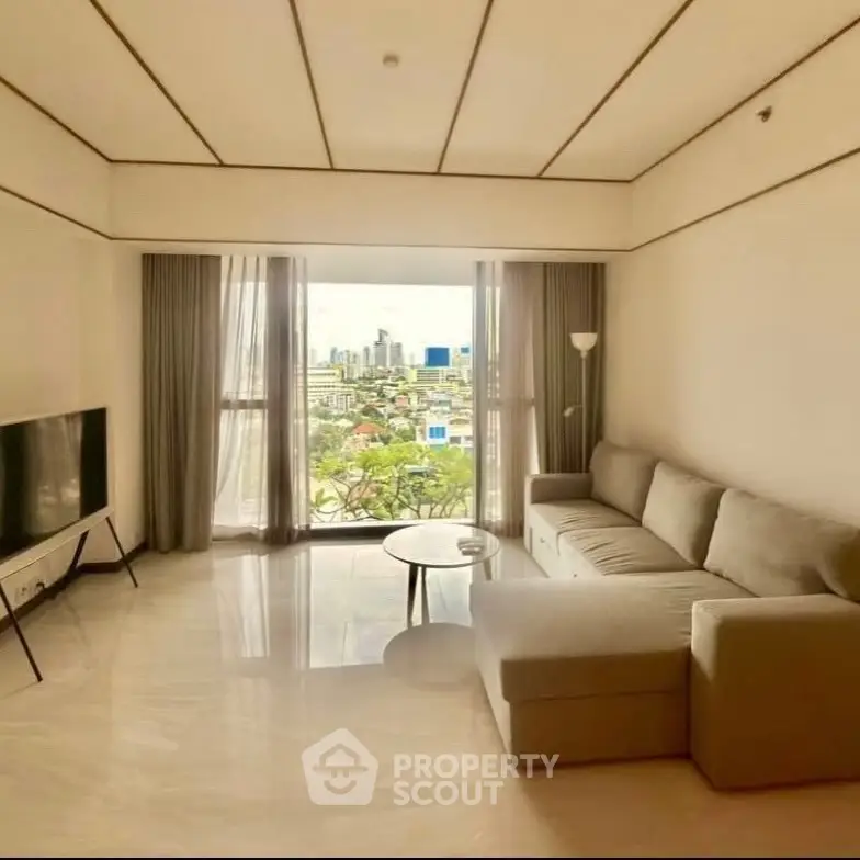 Spacious living room with modern sofa and city view through large windows.