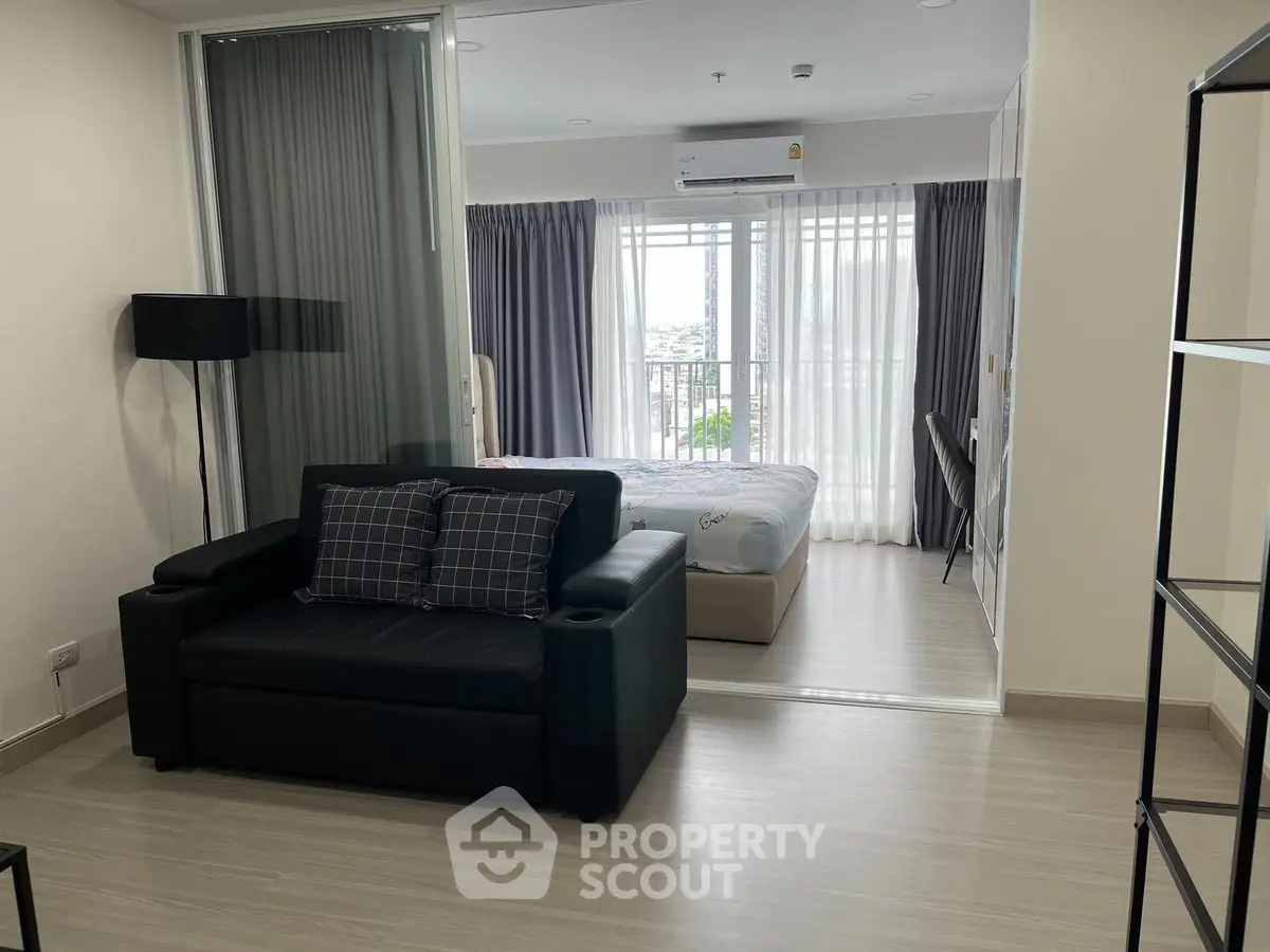 Modern studio apartment with open layout and large windows offering city views.