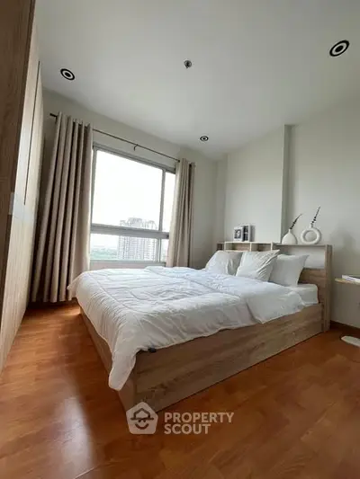 Spacious bedroom with large window and wooden flooring in modern apartment