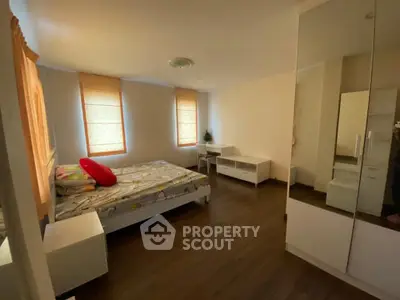 Spacious bedroom with modern decor and ample natural light from large windows.