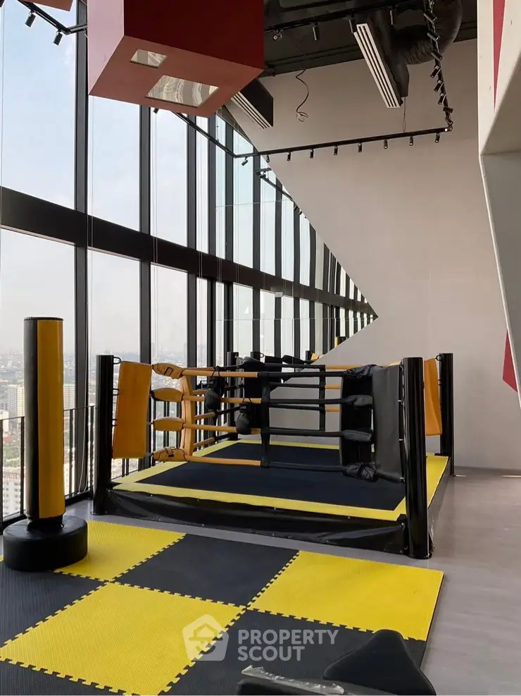 Modern gym with boxing ring and city view in high-rise building