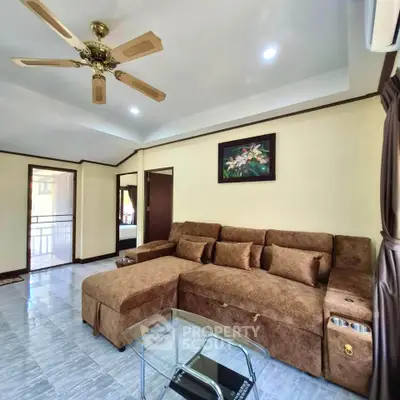 Spacious living room with plush brown sectional sofa and ceiling fan, perfect for relaxation.