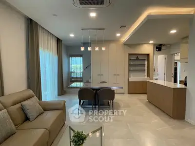 Modern living room with elegant decor and open kitchen layout, featuring stylish lighting and comfortable seating.