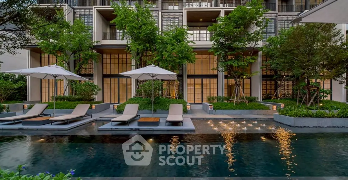 Luxurious modern apartment building with poolside lounge area and lush greenery.
