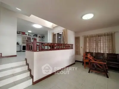 Spacious living area with open layout and natural light, featuring wooden accents and tiled flooring.