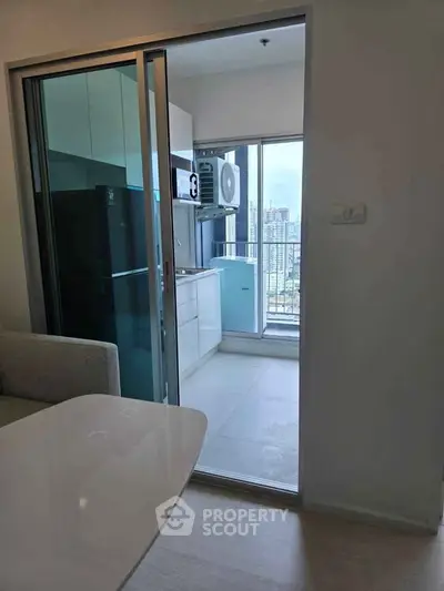 Modern kitchen with sliding glass door and city view, featuring sleek cabinetry and appliances.
