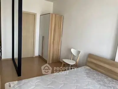 Modern bedroom with minimalist design, featuring a wooden bed frame and wardrobe, perfect for cozy living.