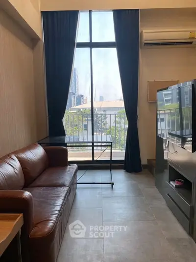 Modern living room with large window and city view, featuring leather sofa and sleek TV setup.