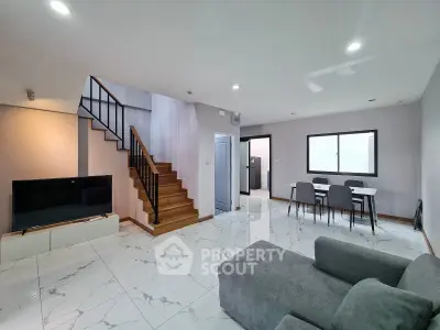 Modern living room with sleek staircase and dining area, featuring elegant marble flooring.