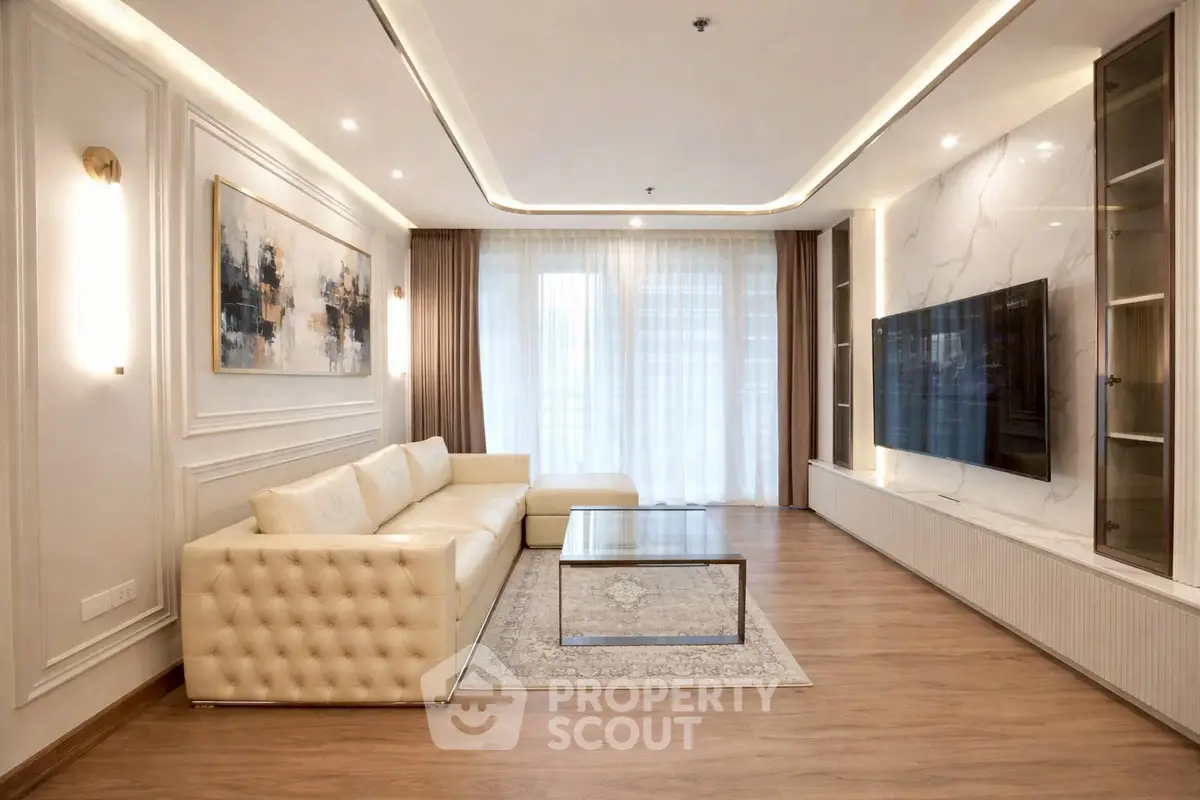 Luxurious living room with elegant decor and large TV, featuring a plush sofa and modern lighting.