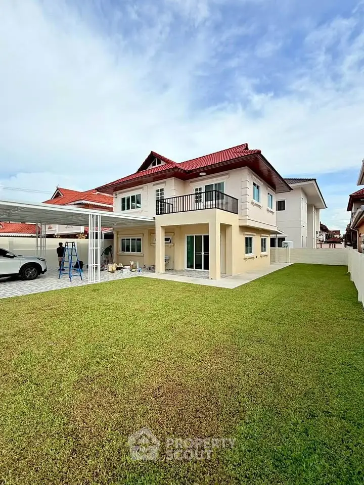 Spacious two-story house with red roof and large backyard lawn, perfect for family living.